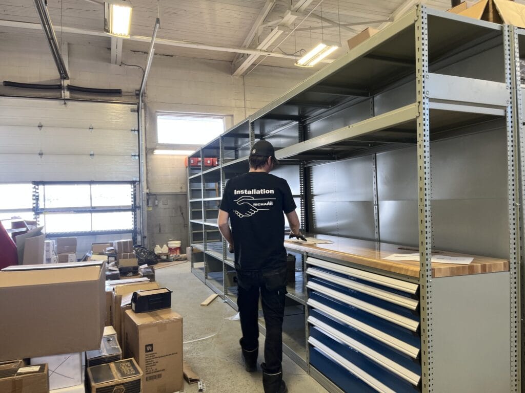 Installateur devant des rayonnages et cabinets à tiroirs fraîchement installés