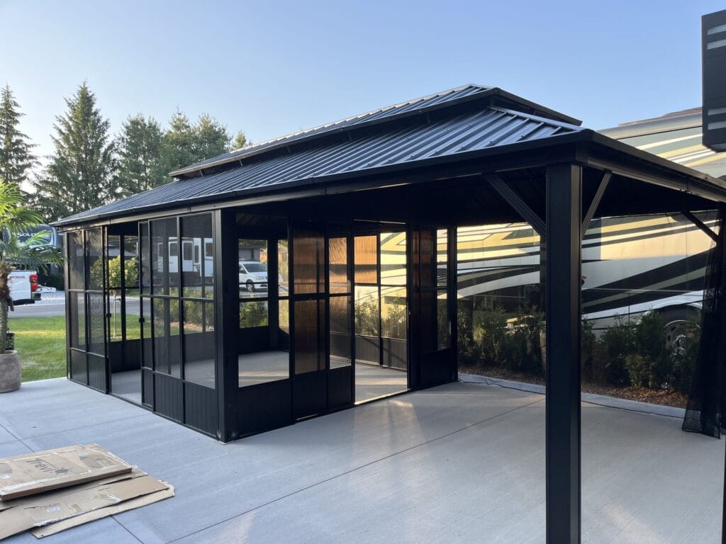Gazebo noir avec murs vitrés assemblé sur une dalle de béton