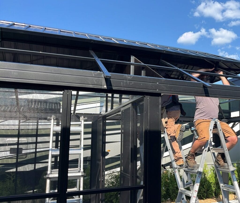 Deux installateurs sur des escabeaux fixant le toit d'un gazebo